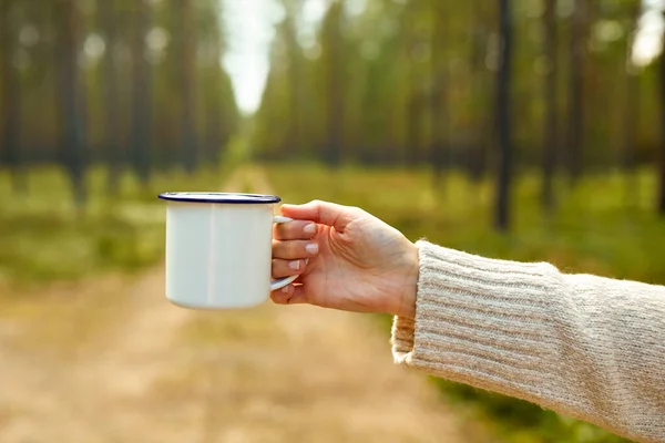 Mano de mujer con taza de té blanco en el bosque — Foto de Stock