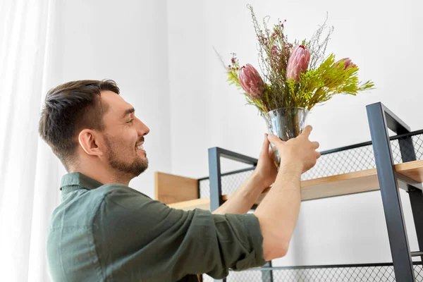 Чоловік прикрашає будинок квітами у вазі — стокове фото