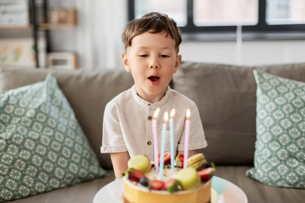 Menino feliz soprando velas no bolo de aniversário — Fotografia de Stock