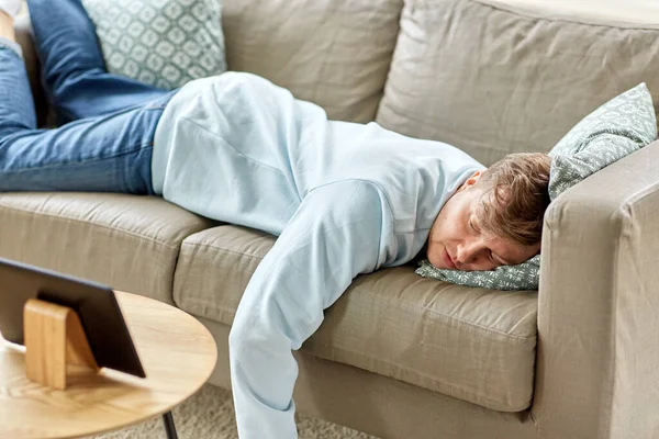 Hombre aburrido con la tableta PC acostado en el sofá en casa — Foto de Stock