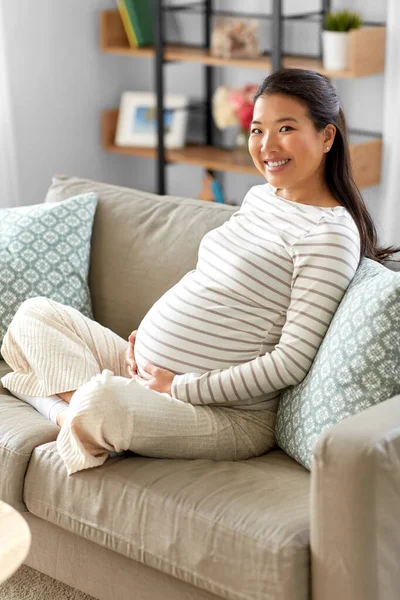 Heureux enceinte asiatique femme assis sur canapé à la maison — Photo