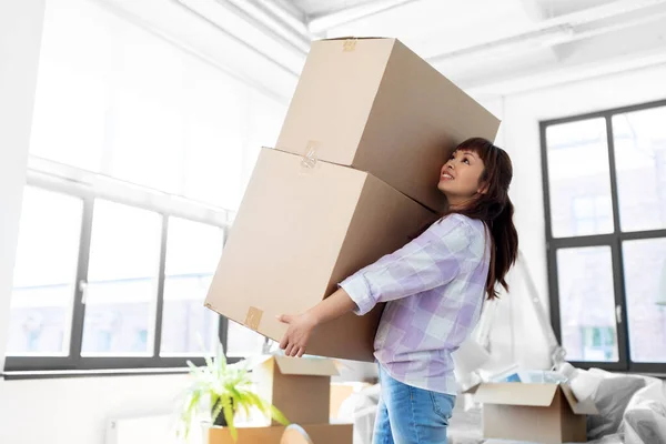 Happy woman holding boxes and moving to new home — Stock Photo, Image