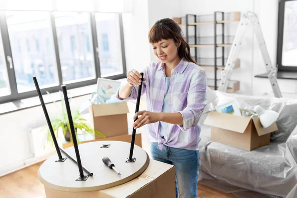 Gelukkig vrouw assemblage salontafel in nieuw huis — Stockfoto