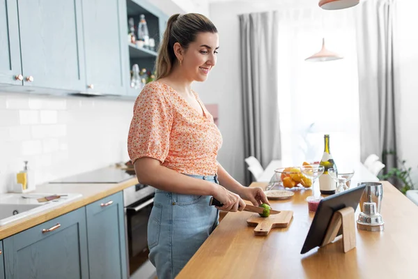 Woman with tablet pc making cocktails at kitchen — Stock Photo, Image