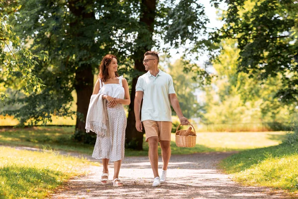 Pareja feliz con cesta de picnic en el parque de verano —  Fotos de Stock