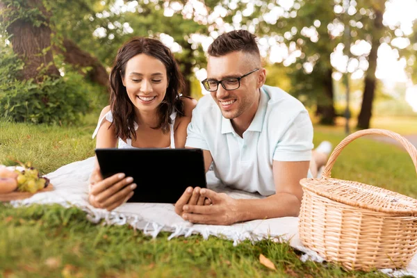 Szczęśliwa para z tabletem na pikniku w parku — Zdjęcie stockowe