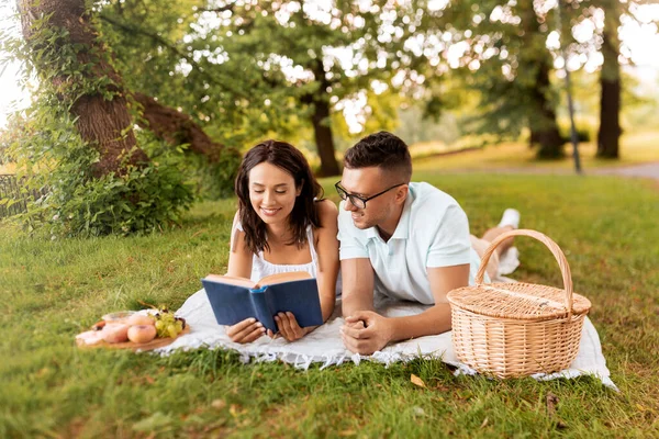 夏の公園でピクニックの本を読んでいる幸せなカップル — ストック写真