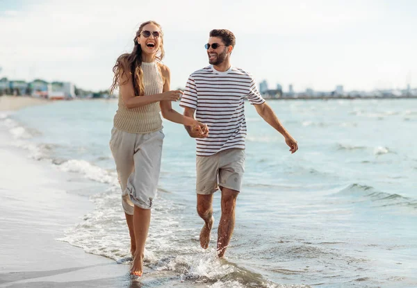 Felice coppia che corre lungo la spiaggia estiva — Foto Stock