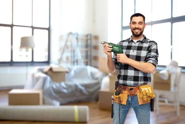 Gelukkige mannelijke bouwer met boormachine en gereedschap thuis — Stockfoto