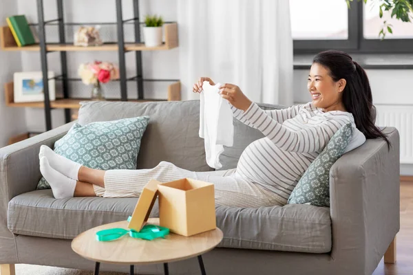 Femme enceinte heureuse avec costume de bébé à la maison — Photo