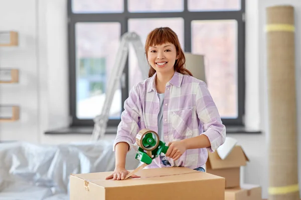 Kvinna med självhäftande tejp förpackning låda på nytt hem — Stockfoto