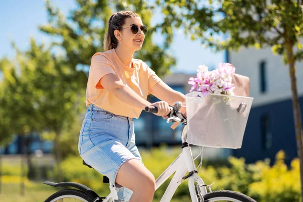 Kobieta z kwiatami w koszu rowerowym w mieście — Zdjęcie stockowe