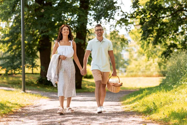 Pareja feliz con cesta de picnic en el parque de verano —  Fotos de Stock