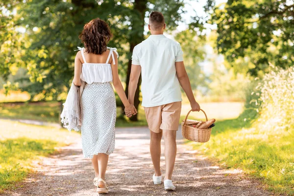 Coppia felice con cestino da picnic al parco estivo — Foto Stock