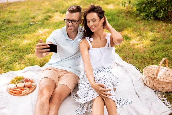Szczęśliwy para biorąc selfie na piknik w parku — Zdjęcie stockowe