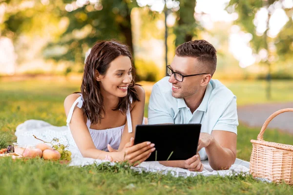 Gelukkig paar met tablet pc op picknick in park — Stockfoto
