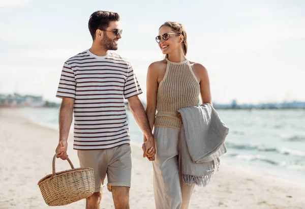 Coppia felice con cestino da picnic passeggiando sulla spiaggia — Foto Stock