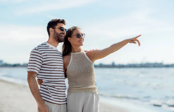 Feliz casal apontando dedo na praia de verão — Fotografia de Stock