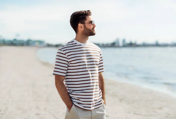 Молодой человек в солнечных очках на летнем пляже — стоковое фото