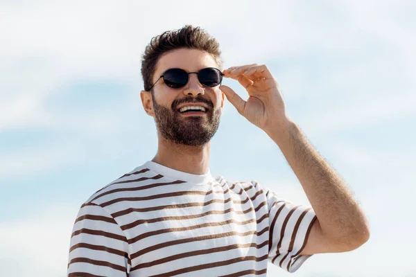 Smiling young man in sunglasses over sky — Stock Photo, Image