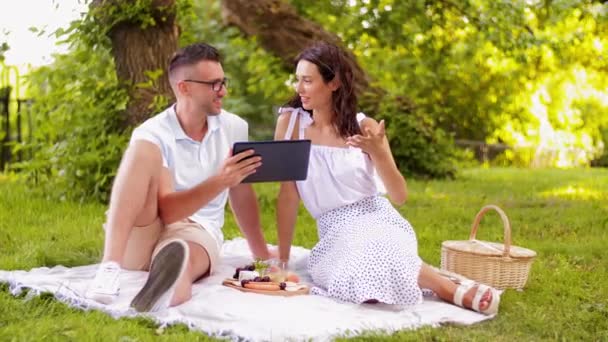 Feliz pareja con PC tableta en el picnic en el parque — Vídeos de Stock