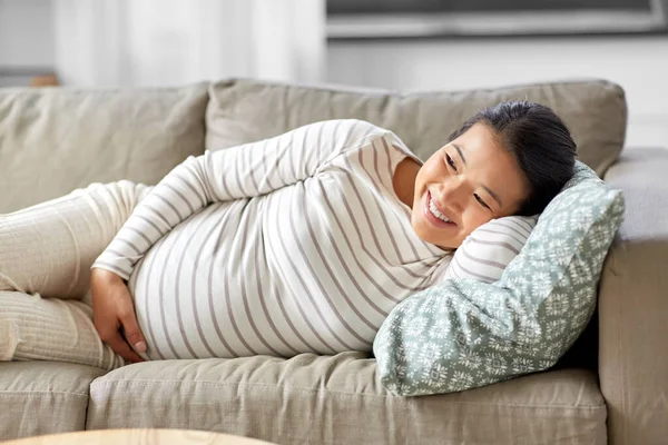 Glad gravid asiatisk kvinna ligger på soffan hemma — Stockfoto