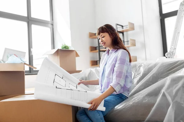 Женщина с чертежами и коробками переезжает в новый дом — стоковое фото