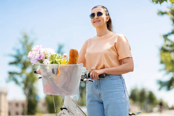 Kvinna med mat och blommor i cykelkorg — Stockfoto