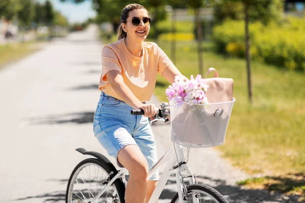 Frau mit Blumen im Fahrradkorb in der Stadt — Stockfoto