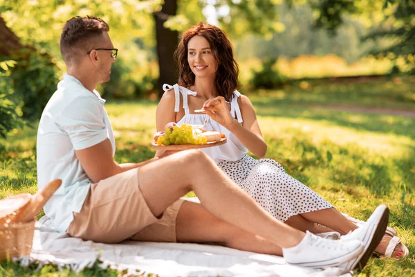 Casal feliz fazendo piquenique no parque de verão — Fotografia de Stock