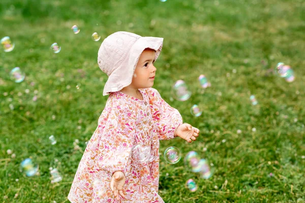 Gelukkig baby meisje spelen met zeepbellen buiten — Stockfoto