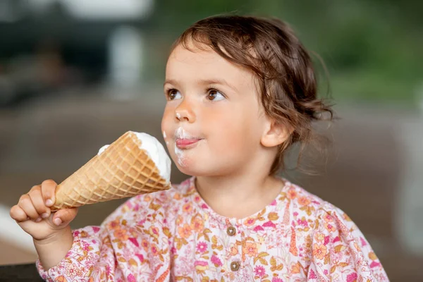 Glad liten flicka äter glass — Stockfoto