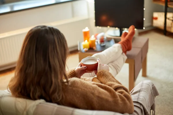 Женщина смотрит телевизор и пьет какао на Хэллоуин — стоковое фото