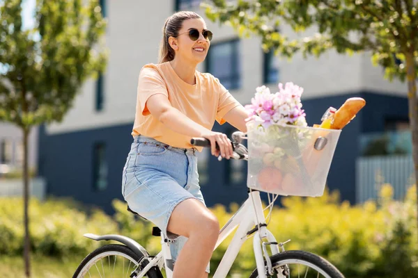 Femme avec de la nourriture et des fleurs dans le panier à vélo — Photo