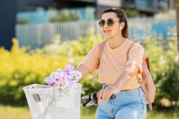 Lycklig kvinna med hörlurar ridning cykel i staden — Stockfoto