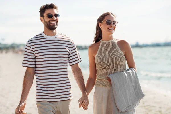 Casal feliz com cobertor andando ao longo da praia — Fotografia de Stock