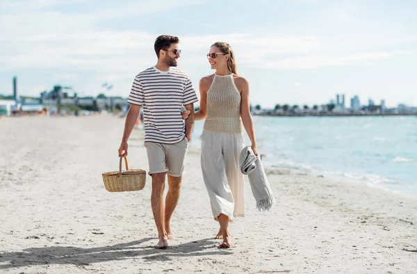 Szczęśliwa para z koszykiem piknikowym spacerująca po plaży — Zdjęcie stockowe