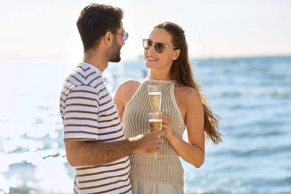 Lyckliga par dricker champagne på sommarstranden — Stockfoto