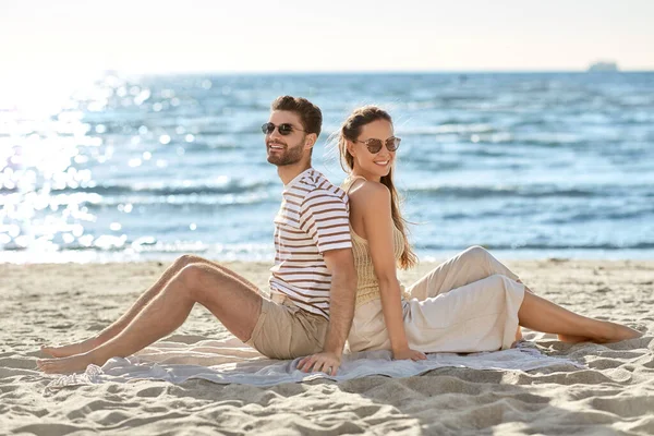 一对快乐的夫妇背靠背地坐在夏天的海滩上 — 图库照片