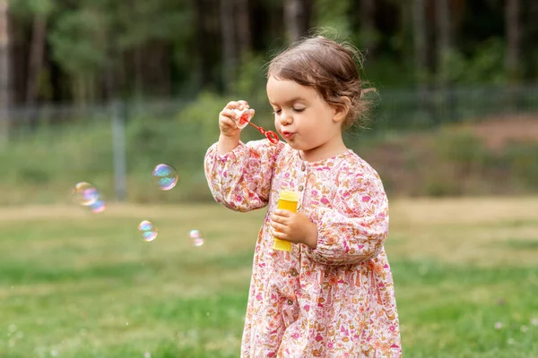 Niña feliz soplando burbujas de jabón en verano —  Fotos de Stock