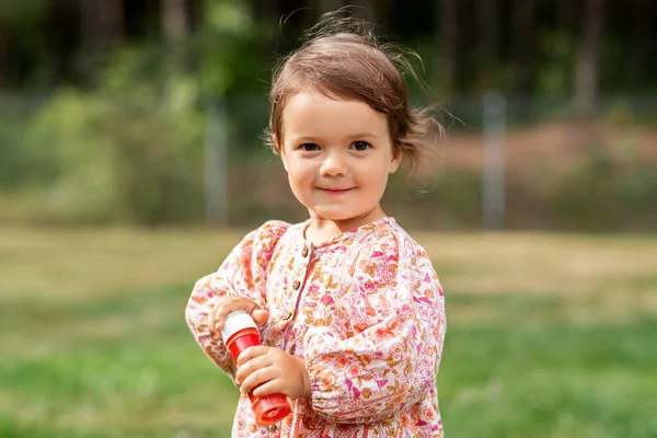 Happy baby girl with soap bubble blower in summer — Stock Photo, Image