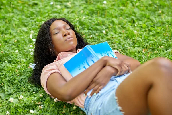 African student girl with book sleeping on grass — Stock Photo, Image