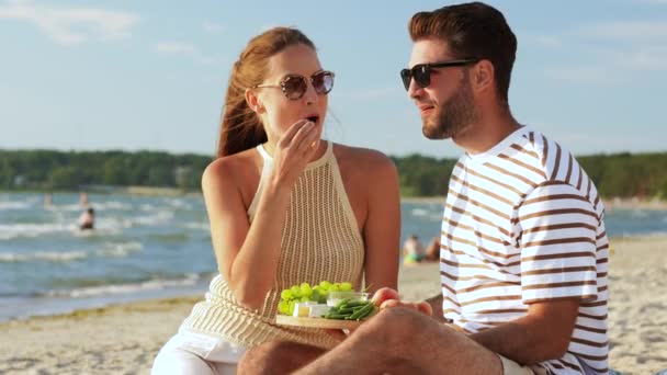 Счастливая пара с едой пикник на пляже — стоковое видео