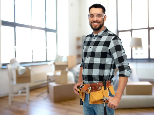 Glücklicher männlicher Baumeister mit Werkzeuggürtel zu Hause — Stockfoto