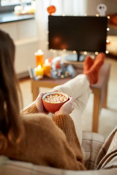 Kobieta ogląda telewizję i pije kakao na Halloween — Zdjęcie stockowe