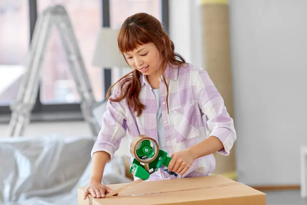 Mujer con cinta adhesiva caja de embalaje en el nuevo hogar —  Fotos de Stock