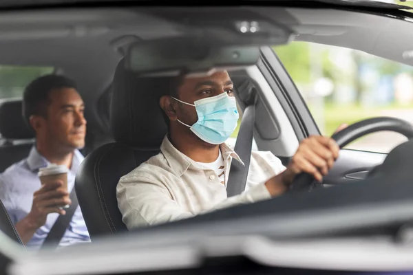 Male driver in mask driving car with passenger — Stock Photo, Image