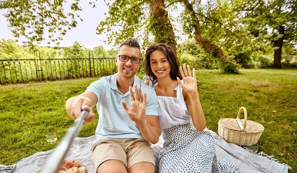 Feliz pareja tomando selfie en el picnic en el parque —  Fotos de Stock
