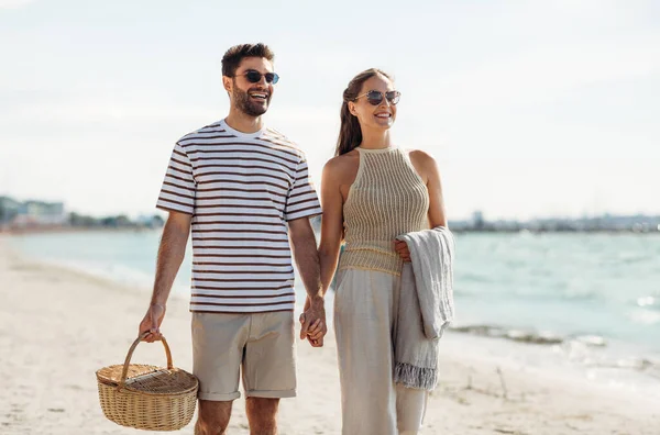 Casal feliz com cesta de piquenique andando na praia — Fotografia de Stock