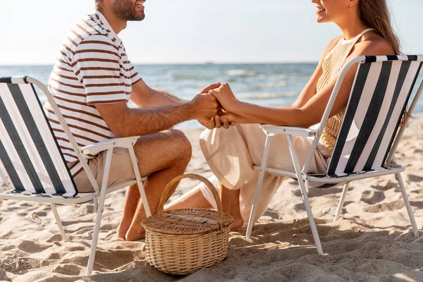 Happy couple sitting in folding chairs on beach — Stock Photo, Image
